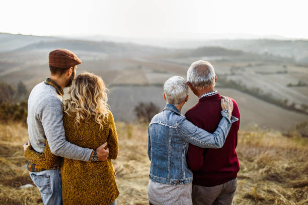 istock Back view of two couples standing embraced on a hill and looking at view. 1225745058