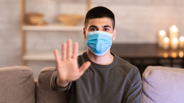 istock Man wearing surgical mask showing stop hand gesture 1225745133