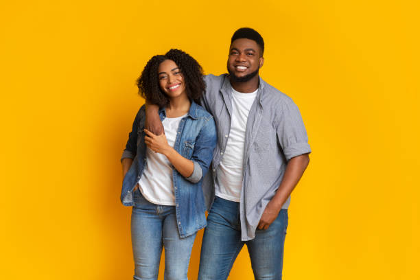 istock Smiling black man posing with girlfriend over yellow background in studio 1225745182