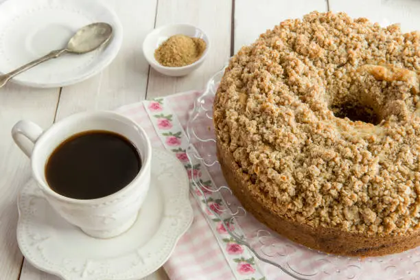 Homemade cinnamon streusel coffee cake on rustic white wooden table.