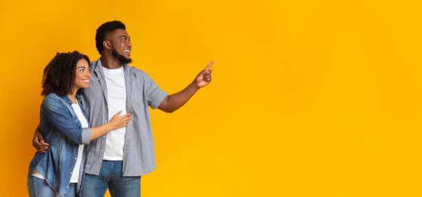 istock Promo Offer. Smiling Black Couple Cuddling And Pointing At Copy Space 1225746631