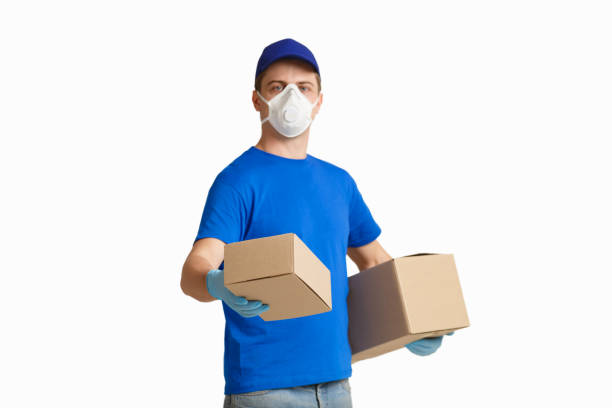 istock Deliveryman in medical mask holds out box 1225747811