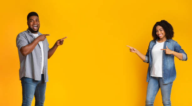 Happy millennial black couple pointing at copy space in the middle