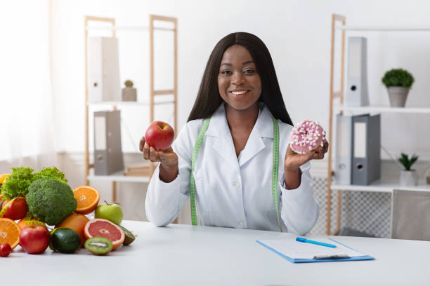 istock Pretty dietary doctor holding donut and apple in her hands 1225752817