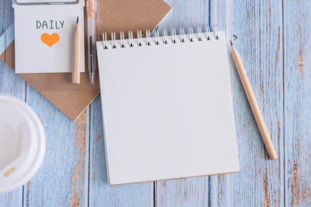 Top view white binder blank notebook or diary or journal for writing text and message with pencil and coffee cup on blue pastel wood background with copy space. Still lifestyle photo concept.