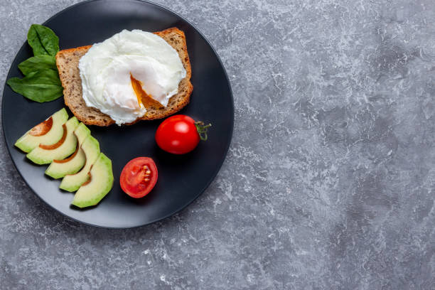 Toast bread with eggs, cherry tomatoes, avocado and greens on wooden cutting board food, eating and breakfast concept - toast bread with eggs, cherry tomatoes, avocado and greens on wooden cutting board egg cherry tomato rye stock pictures, royalty-free photos & images