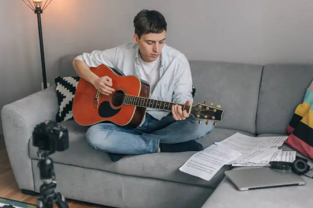 Photo of Young man playing guitar for his YouTube channel