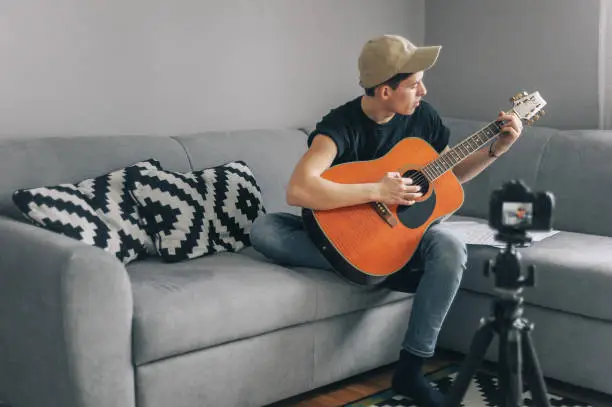 Photo of Young man playing guitar for his YouTube channel