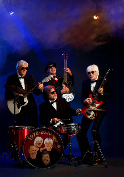 istock Musician group guitarist and drummer Active senior Handsome man playing guitar and drum. Best friends. Blue  background, with rays of light and special effects smoke. 1225756727