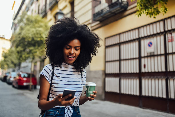 istock Beautiful Afro girl walking and using smartphone 1225759297