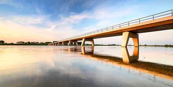 Springtime sunset over a bridge over the Reevediep lake during a beautiful evening in May near Kampen in Overijssel, The Netherlands.