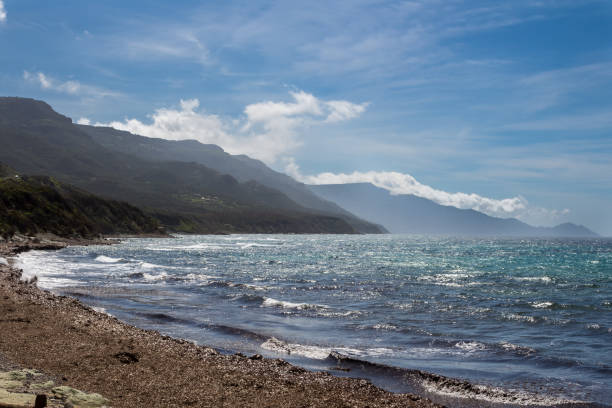 Waves of the Mediterranean sea with a white foam. Sunny spring day with white clouds on the blue sky. East coast south of Alghero, Beach of Hope (Spiaggia della Speranza, Sardinia, Italy.