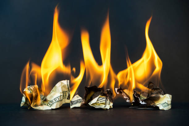 istock Crumpled dollar bills burning fire on a dark background 1225764918