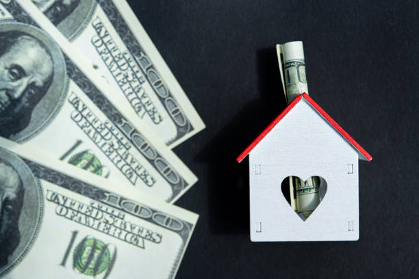 istock Model of a house with dollars bill on black background 1225765780