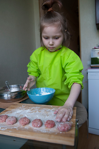 Quarantine isolation due to pandemic COVID-19. A five-year-old girl sculpts minced meat patties.