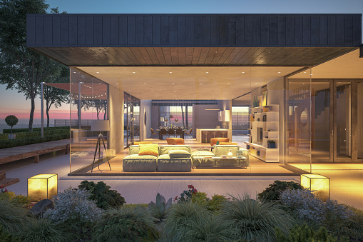 3D rendering with a contemporary cubic house with garden and a lounge area by the pool in the evening
