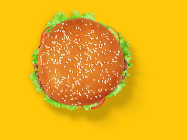 istock fresh tasty burger on yellow background. Top view 1225769684