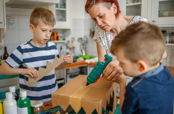 istock Mom and kids making a cardboard dinosaur costume 1225772703