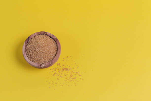 istock Brown sugar heap in bowl on yellow background 1225774430