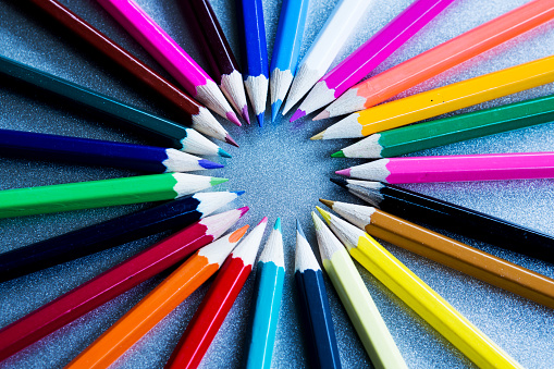 close-up of colored pencils in a circle on a grey background