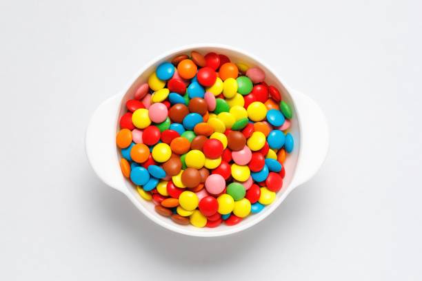 istock Colorful chocolate candy pills in bowl isolated on white background. Top view 1225779504