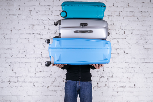 Man holding three heavy suitcases in hand. Travel light.