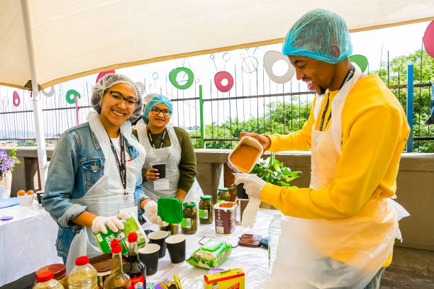 i volontari della comunità soup kitchen preparano i pasti per i bambini africani nell'orfanotrofio - homelessness food in a row people foto e immagini stock