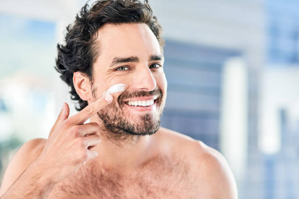 I make sure my skin is always in perfect condition Cropped shot of a handsome young man applying moisturizer to his face inside the bathroom at home body care and beauty photos stock pictures, royalty-free photos & images
