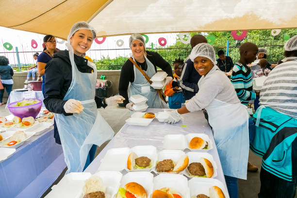 voluntários de divulgação da comunidade da cozinha de sopa preparando refeições para crianças africanas em orfanato - homelessness food in a row people - fotografias e filmes do acervo