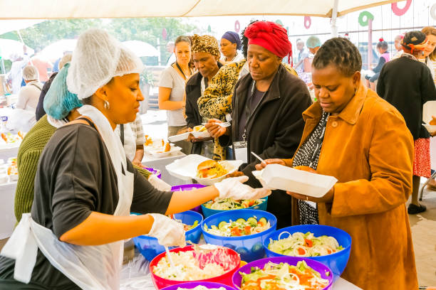 スープキッチンコミュニティアウトリーチケータリングスタッフは、アフリカの子供のための食事を料理 - homelessness food in a row people ストックフォトと画像