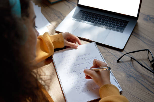 Teen girl college student wear headphones studying from home writing in workbook solving equations learning math sits at desk. Teenage school pupil learn online on laptop, close up over shoulder view. Teen girl college student wear headphones studying from home writing in workbook solving equations learning math sits at desk. Teenage school pupil learn online on laptop, close up over shoulder view. insta stock pictures, royalty-free photos & images