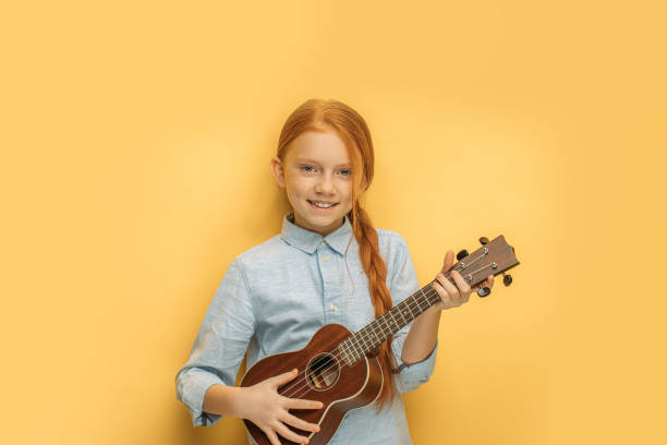 istock beautiful girl learns to play ukulele 1225784443