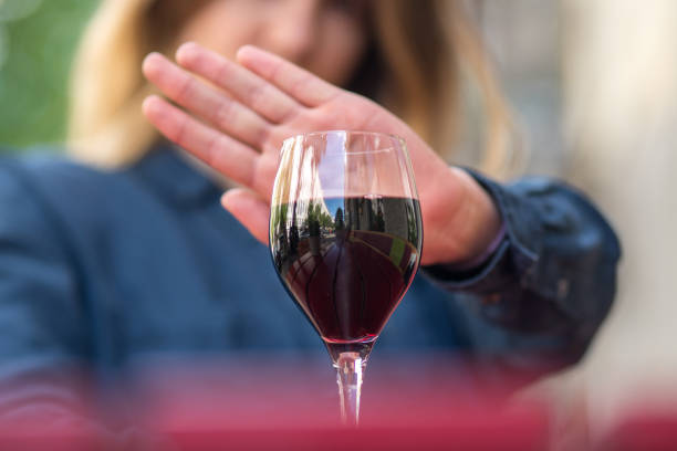 Woman with hand gesture refusing glass of wine or alcohol. A woman at the table gestures with her hand to refuse a glass of red wine sobriety stock pictures, royalty-free photos & images