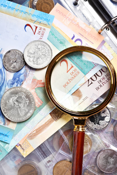 istock Old silver coins and venezuelan notes with magnifying glass 1225790253