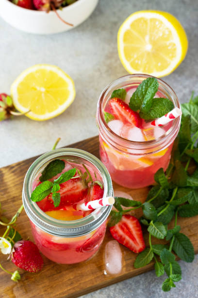 istock Summer drink refreshing. Lemonade with fresh strawberries, ice and lemons on a light stone countertop. 1225791690