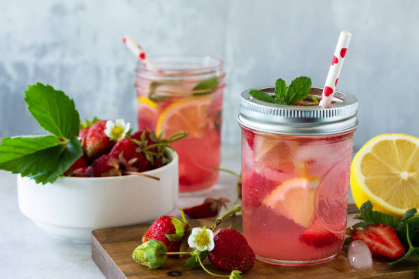 istock Summer drink refreshing. Lemonade with fresh strawberries, ice and lemons on a light stone countertop. 1225791692