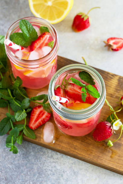 istock Summer drink refreshing. Lemonade with fresh strawberries, ice and lemons on a light stone countertop. Copy space. 1225791694