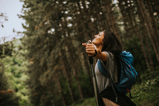 istock Young woman spreading arms and enjoying backpacking travel in the woods 1225793109