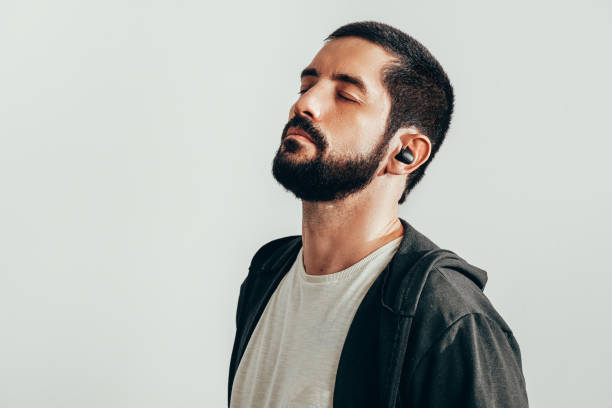 Portrait of a young bearded man wearing sports clothes and wireless earphones. Portrait of a young bearded man wearing sports clothes and wireless earphones. in ear headphones stock pictures, royalty-free photos & images