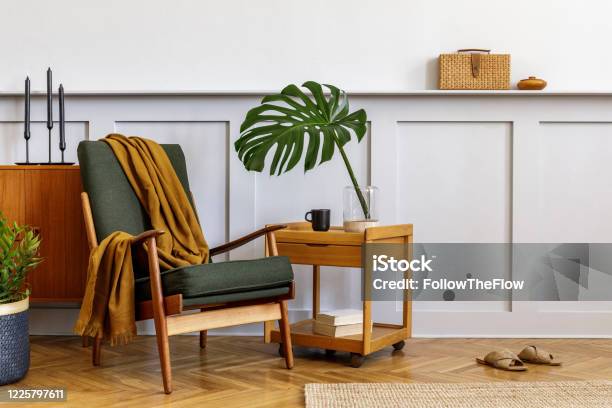 Interior Design Of Stylish Living Room With Vintage Green Armchair Wooden Coffee Table Furniture Grey Wall Shelf Carpet Plants Leaves In Vase Book Copy Space And Elegant Personal Accessories Stock Photo - Download Image Now