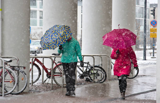 Umbrellas in snowfall Espoo, Finland – April 16, 2020: Pedestrians equipped with umbrellas. Spring day has turned to snowfall. Finland. bicycle rack photos stock pictures, royalty-free photos & images