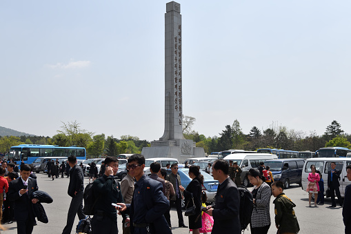 Pyongyang, North Korea - May 1, 2019: People gather to celebrate May 1st Labor Day on the Pyongyang street. Focus on the propaganda stella.