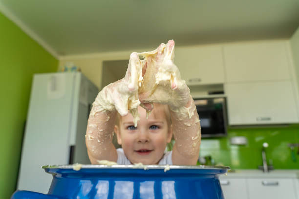istock Baby kneads dough in a saucepan 1225800980