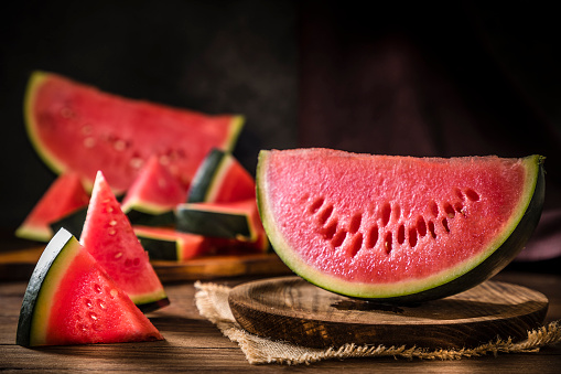 Front view of some slices of watermelon on a dark brown wooden table. Low key DSLR photo taken with Canon EOS 6D Mark II and Canon EF 24-105 mm f/4L