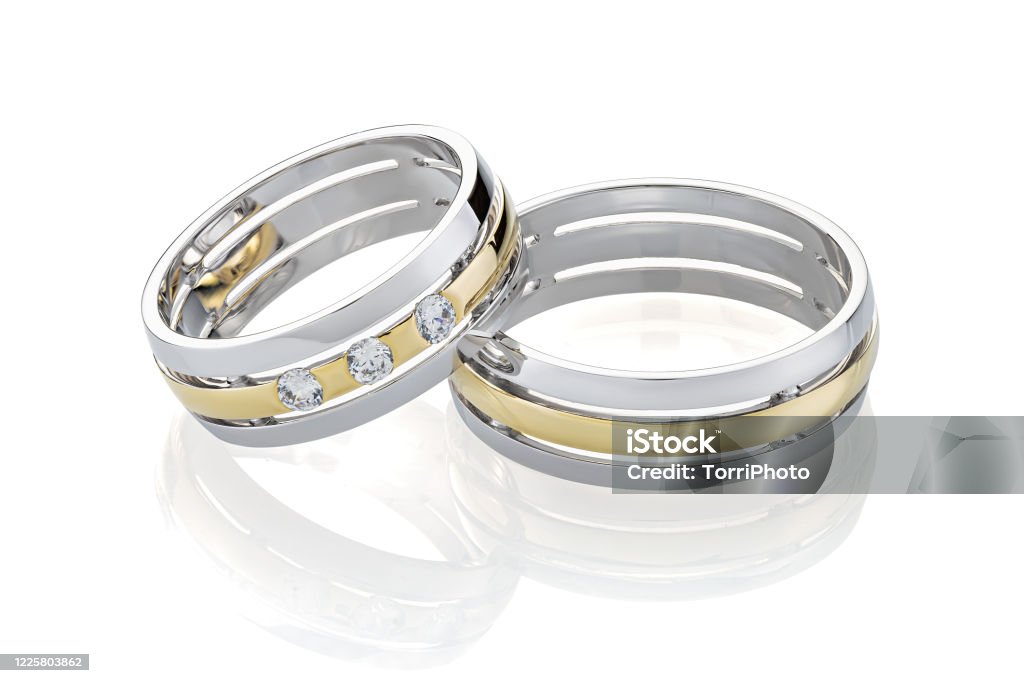 Pair of wedding silver ring and gold rings decorated with diamonds isolated on white background Pair of wedding silver ring and gold rings decorated with diamonds isolated on white background. Wedding ring bands with combined white and yellow gold design Wedding Ring Stock Photo