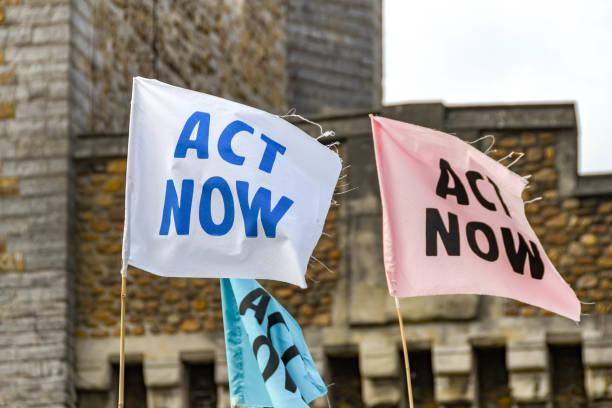 "Act now" banners in a climate change protest in Cardiff city centre as part of an Extinction Rebellion demonstration CARDIFF, WALES - JULY 2019: The large demonstration took place over 3 days bring disruption to the city centre climate crisis photos stock pictures, royalty-free photos & images