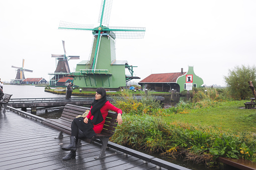 asian beautiful traveler enjoy with her vacation with of windmills background in Amsterdam