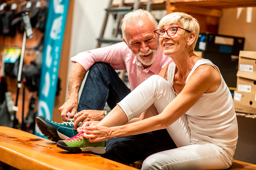 Senior couple choosing rock climbing boots together in an outdoor equipment store.