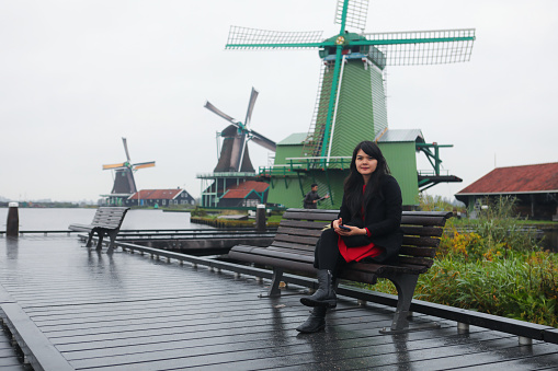 asian beautiful traveler enjoy with her vacation with of windmills background in Amsterdam