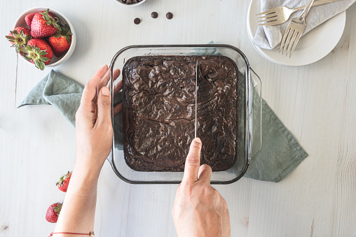Hands of a woman cutting baked brownies
